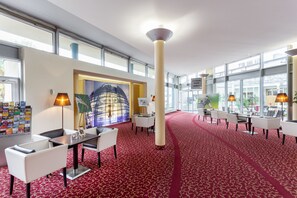 A spacious lobby with a red carpet, modern furniture, and large windows offering views of the city. - Abacus Tierpark Hotel Berlin (Berlin)