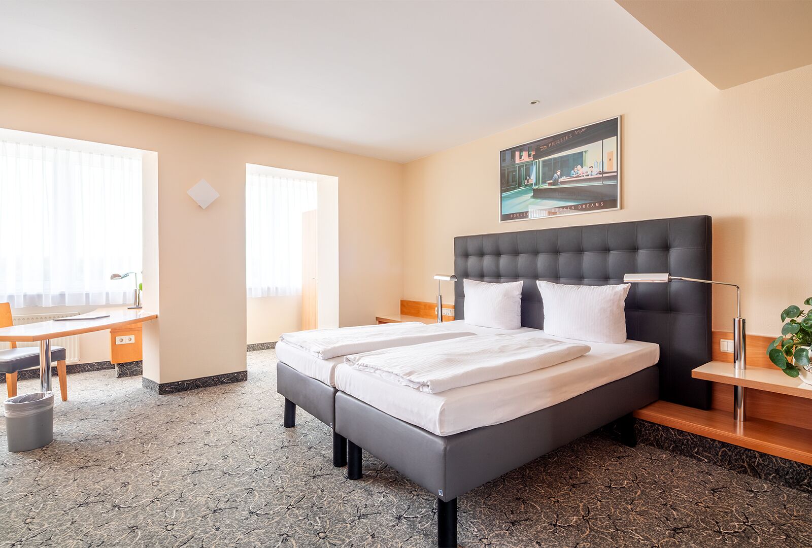 Hotellihuone, jossa on suuri sänky, työpöytä ja tuoli.