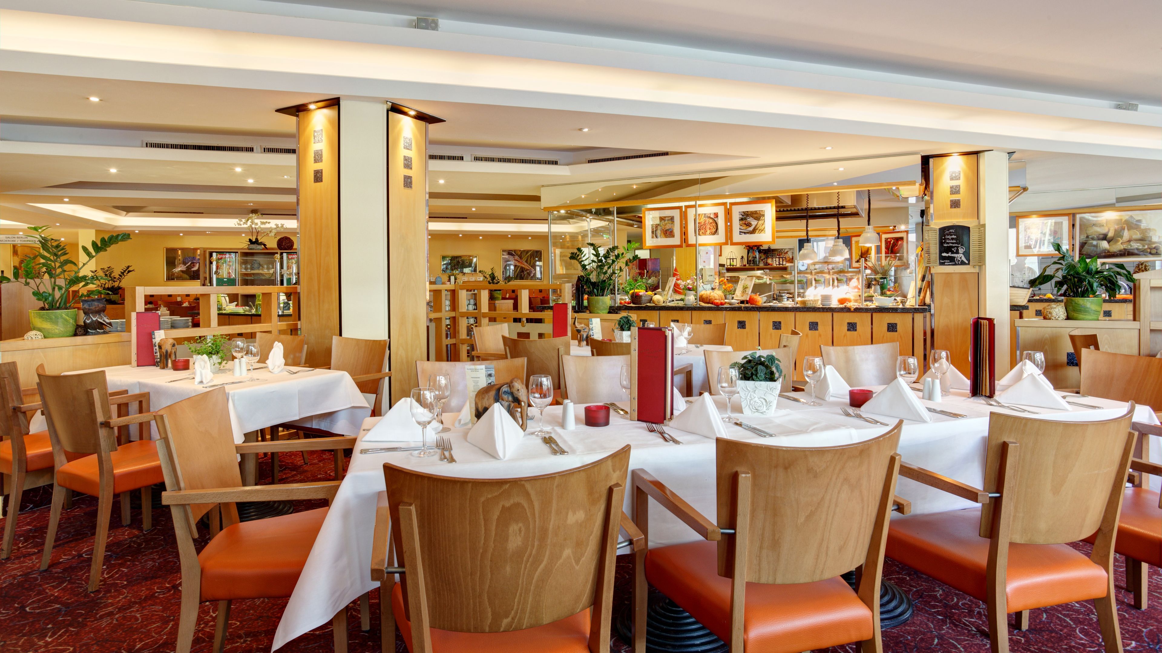 A restaurant with wooden furniture, white tablecloths, and orange chairs.