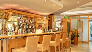 A bar area with wicker chairs, shelves of liquor bottles, and a chalkboard menu. - Abacus Tierpark Hotel Berlin (Berlin)