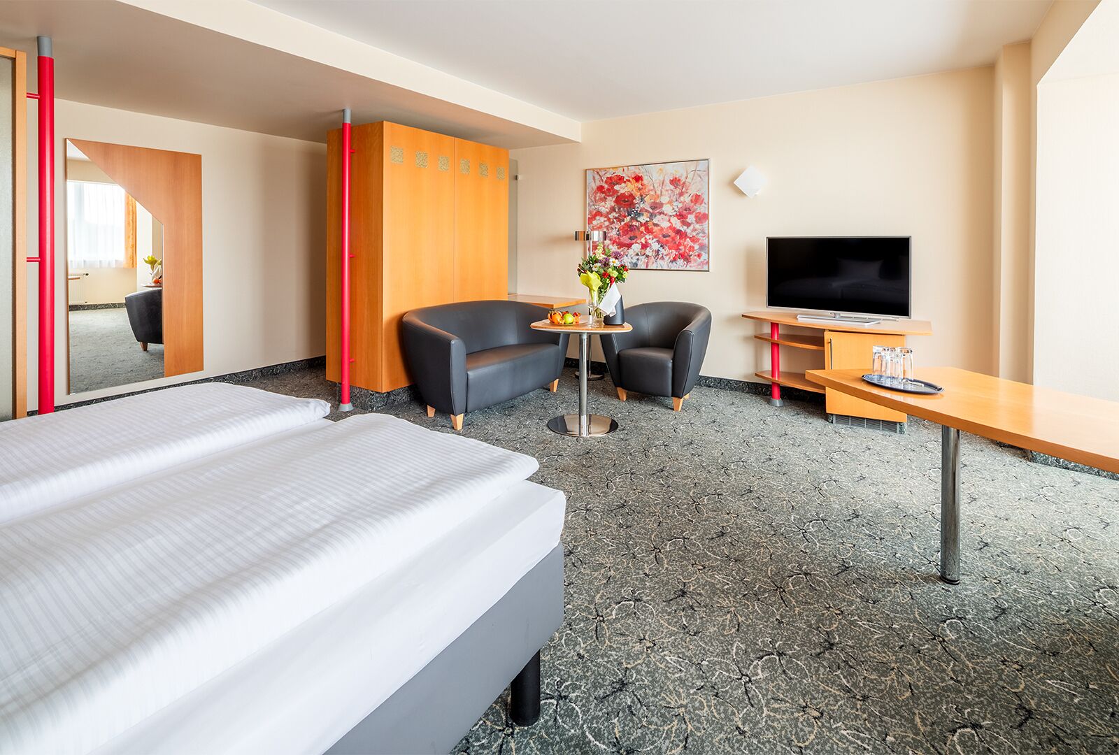 A hotel room with a bed, a desk, a TV, a sofa, and a chair.