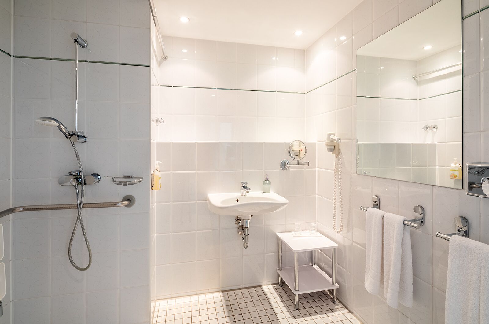 Un baño moderno con ducha, lavamanos y espejo.