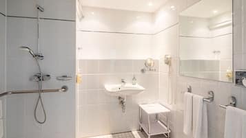 Un baño moderno con ducha, lavamanos y espejo.