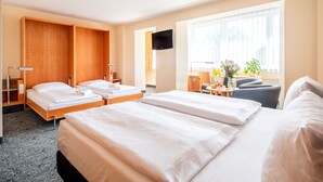 A hotel room with two beds, a TV, a desk with a chair, and a window with curtains. - Abacus Tierpark Hotel Berlin (Berlin)