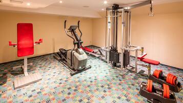 Un gimnasio con equipo de ejercicio, un banco rojo y un suelo estampado.