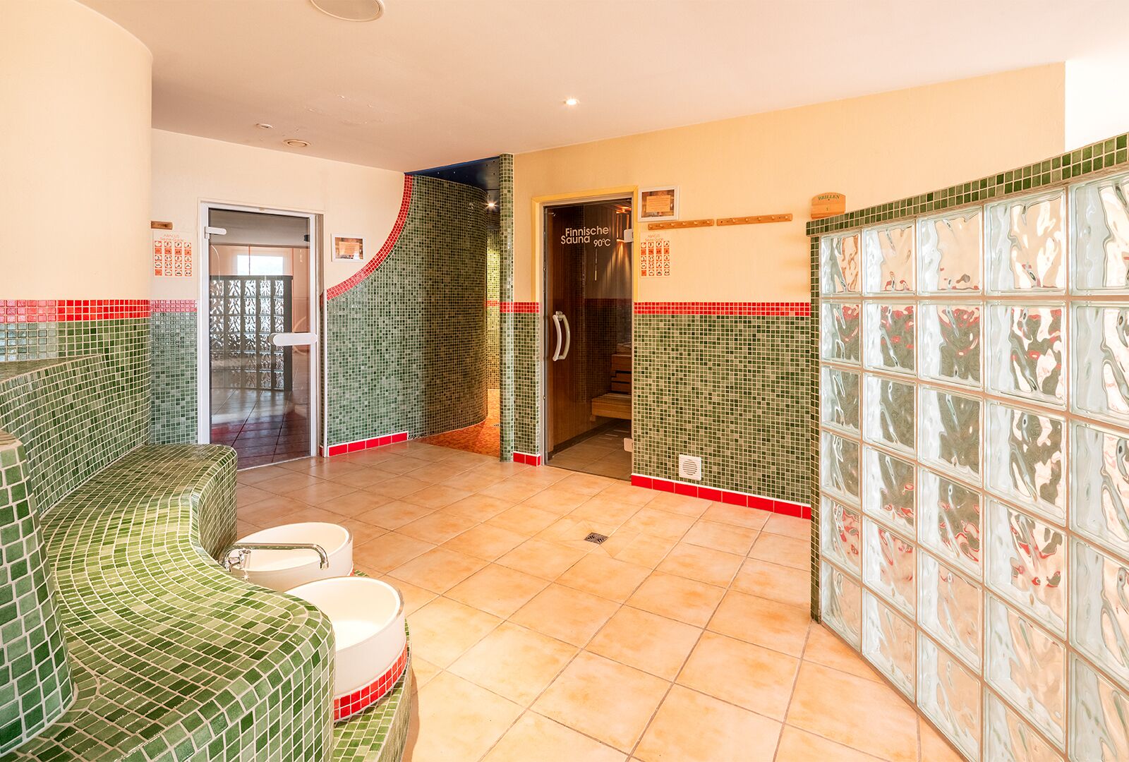 Un baño con pared de mosaico verde, una bañera blanca y zona de ducha.
