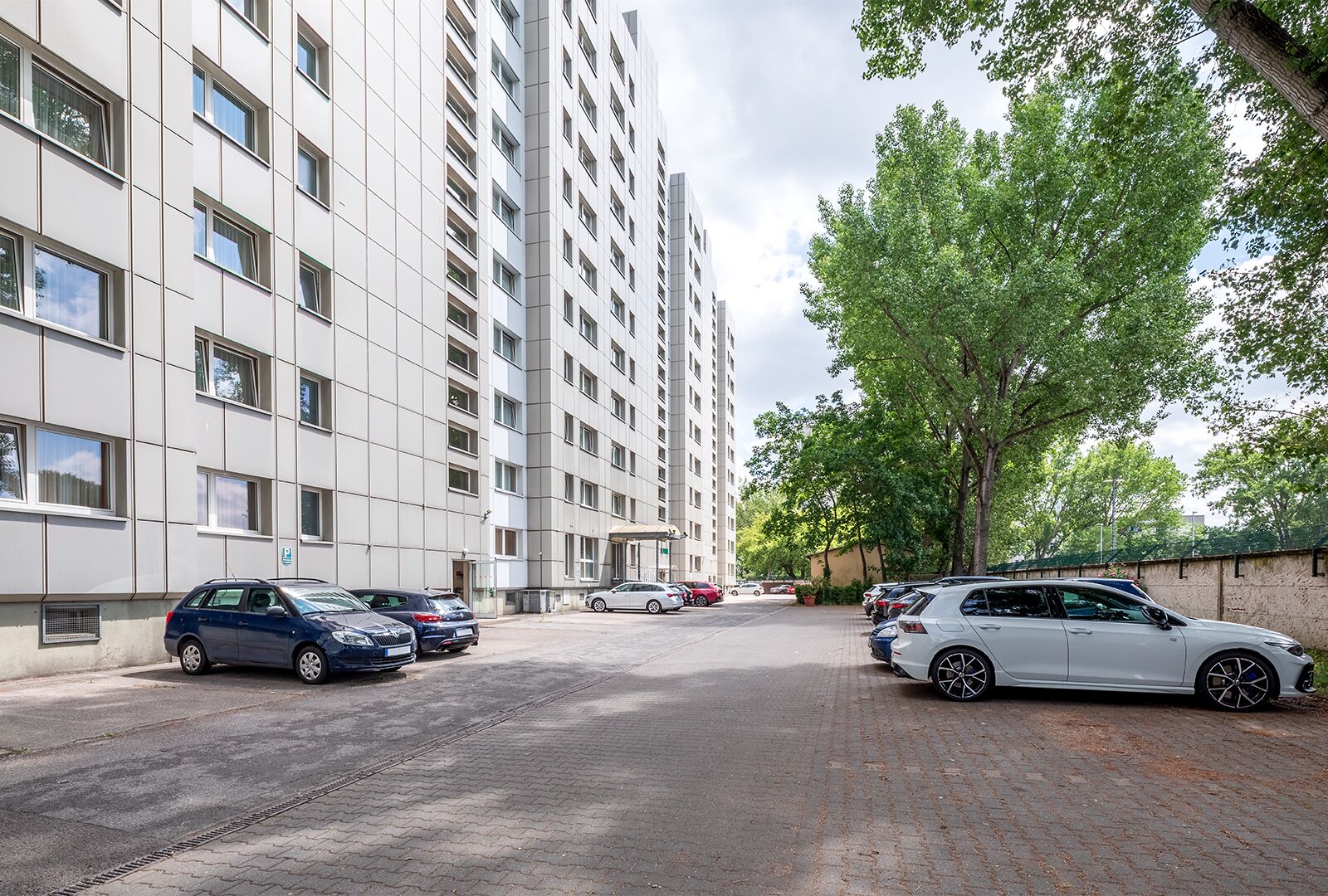 Un edificio residenziale a più piani con un'area di parcheggio antistante.