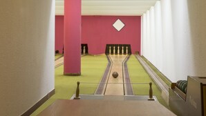 Uma pista de boliche com alamedas verdes, paredes rosa e teto branco.