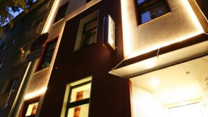 A building with multiple windows and a door, illuminated by artificial lighting. - Hotel Am Volksgarten (Düsseldorf)
