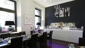 A dining area with a black and white wall art, a chandelier, and a counter with various items. - Hotel Am Volksgarten (Düsseldorf)