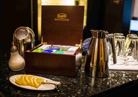 Un juego de té sobre una encimera de mármol, con una caja que indica 'Rongfeldi Selected Tea Since 1825'.