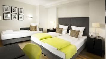 Habitación de hotel con dos camas, un escritorio y una silla. Hay cuadros en la pared y una lámpara en cada mesita de noche.