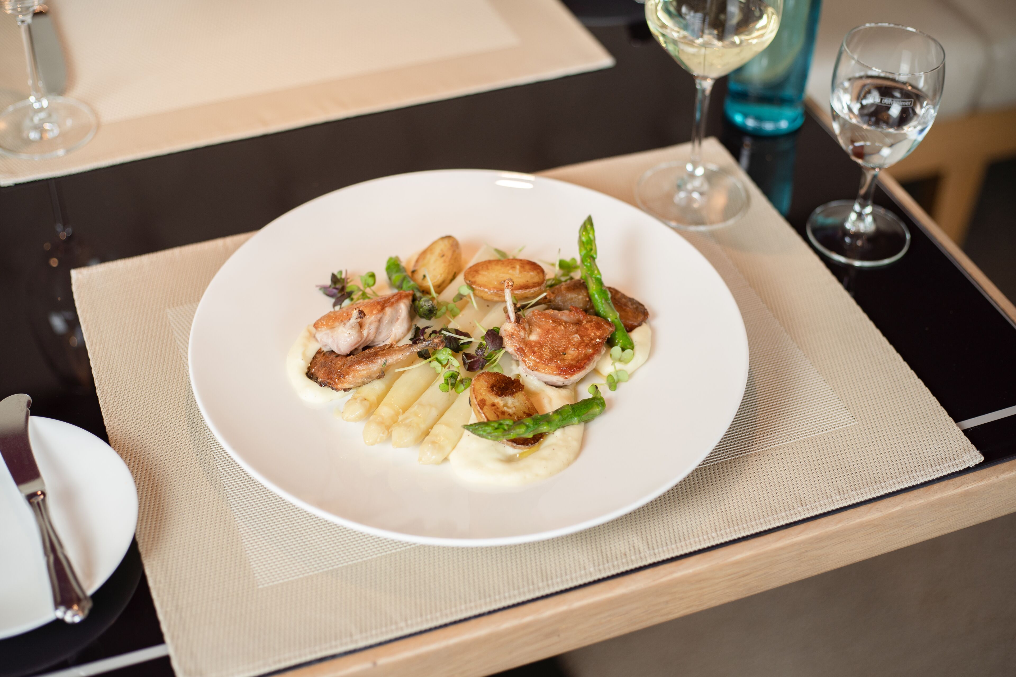 A white plate with food on a table, accompanied by a fork and knife.