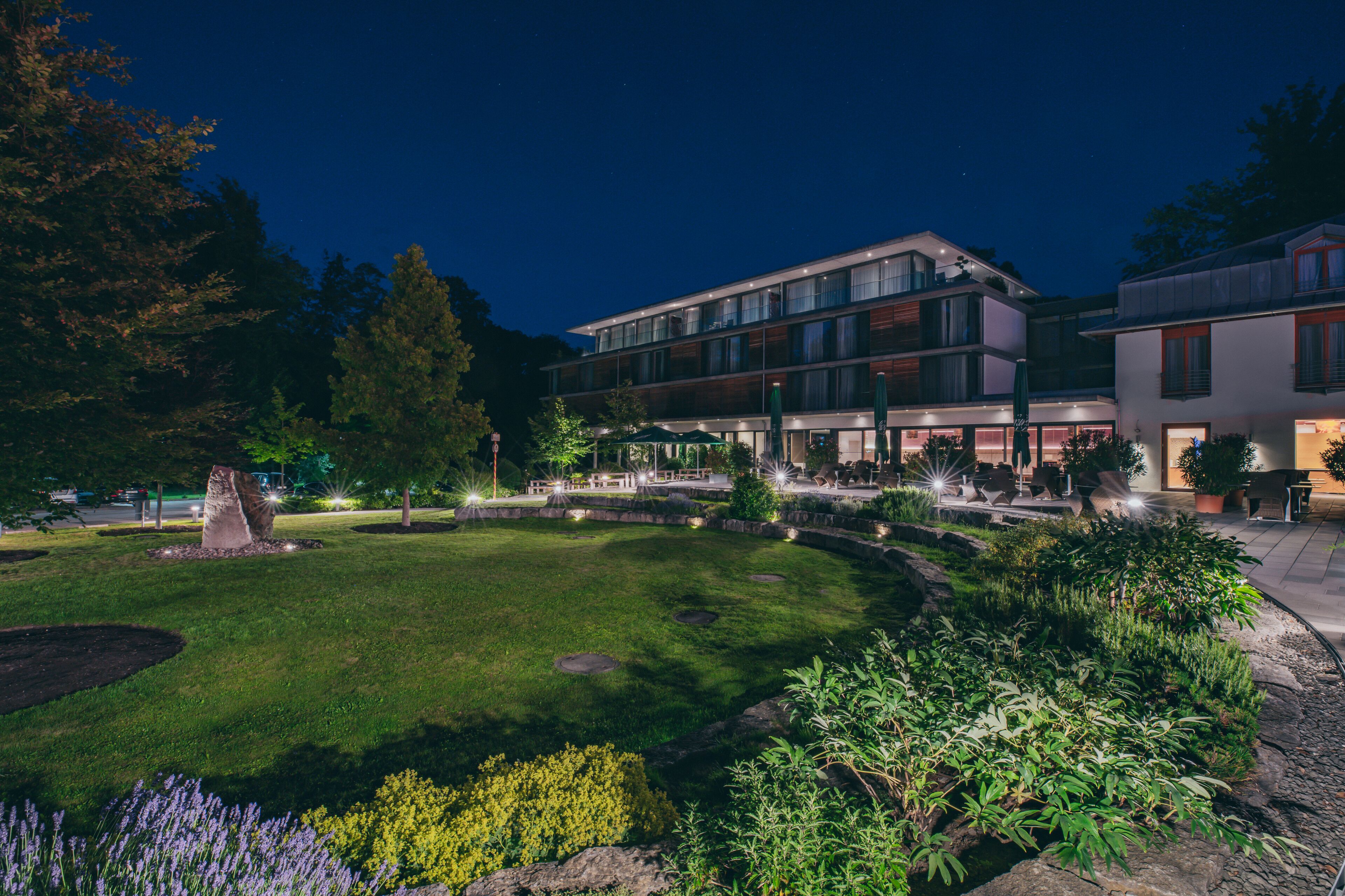 A modern hotel with a landscaped courtyard, outdoor seating area, and a well-maintained garden.