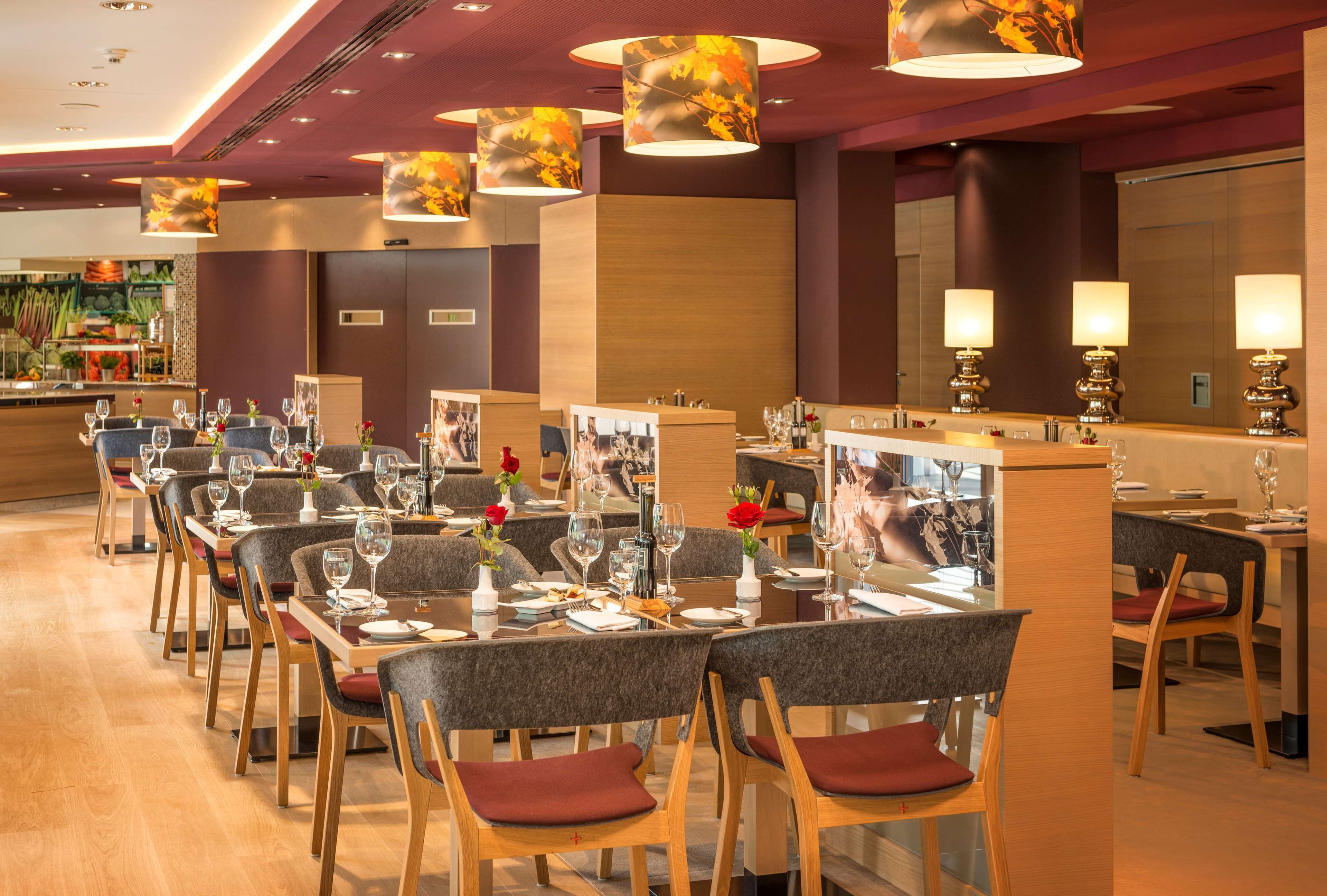 A restaurant with multiple tables and chairs, each set with wine glasses and plates.