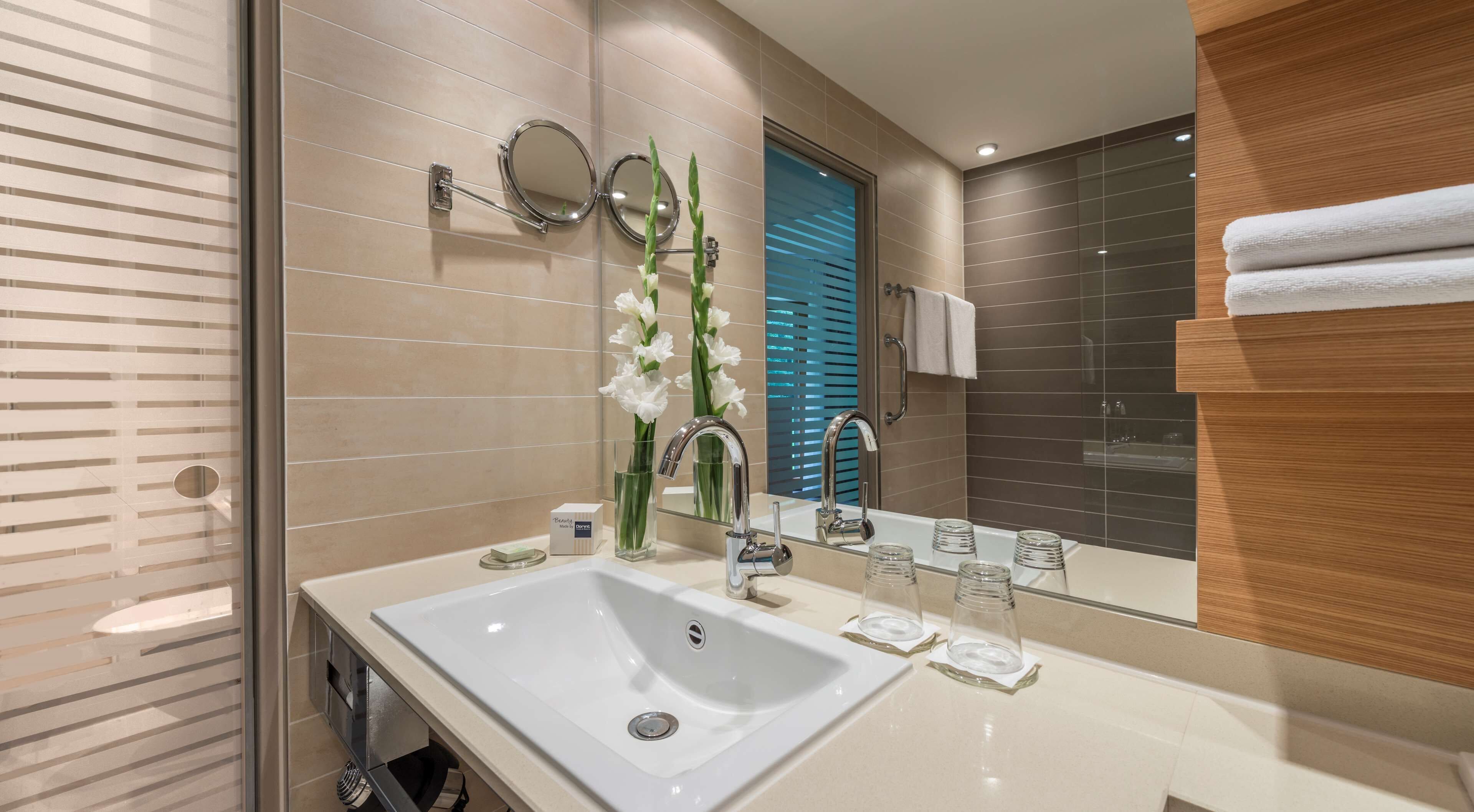 Ein modernes Badezimmer mit einem großen Waschbecken, einem Spiegel und einer Duschkabine aus Glas.