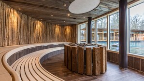 A modern spa area with wooden walls, a curved bench, and a central wooden structure.