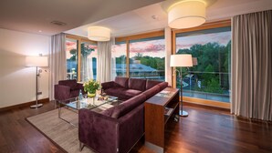 A modern living room with a purple sofa, glass coffee table, and a view of a building through large windows.