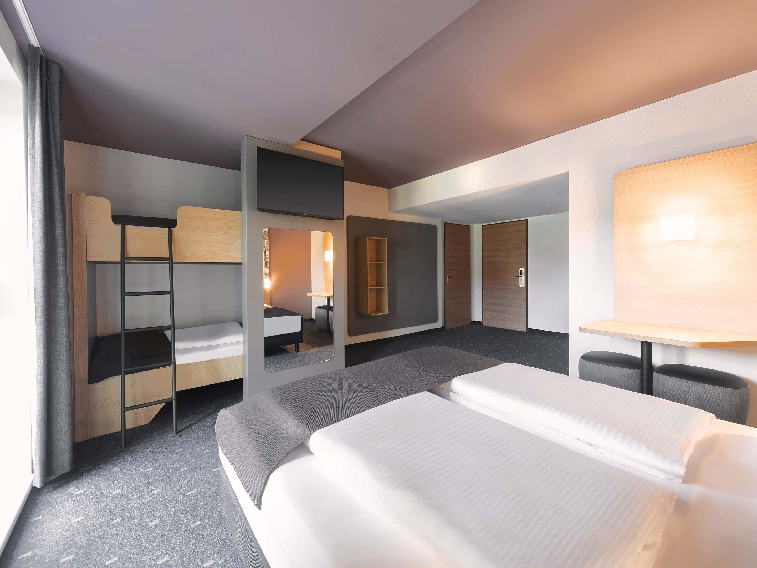 Una habitación de hotel moderna con una cama grande, un escritorio, una silla, un armario y un espejo.