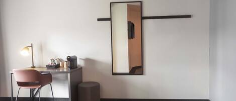 Una habitación de hotel moderna con escritorio, silla, lámpara y un espejo grande en la pared.