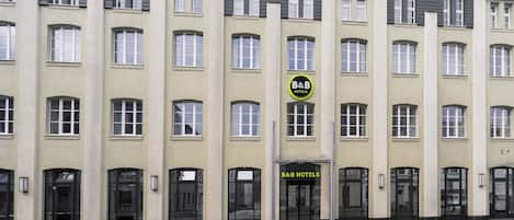 A multi-story hotel building with a symmetrical facade, featuring a central entrance with a sign for B&B Hotels.