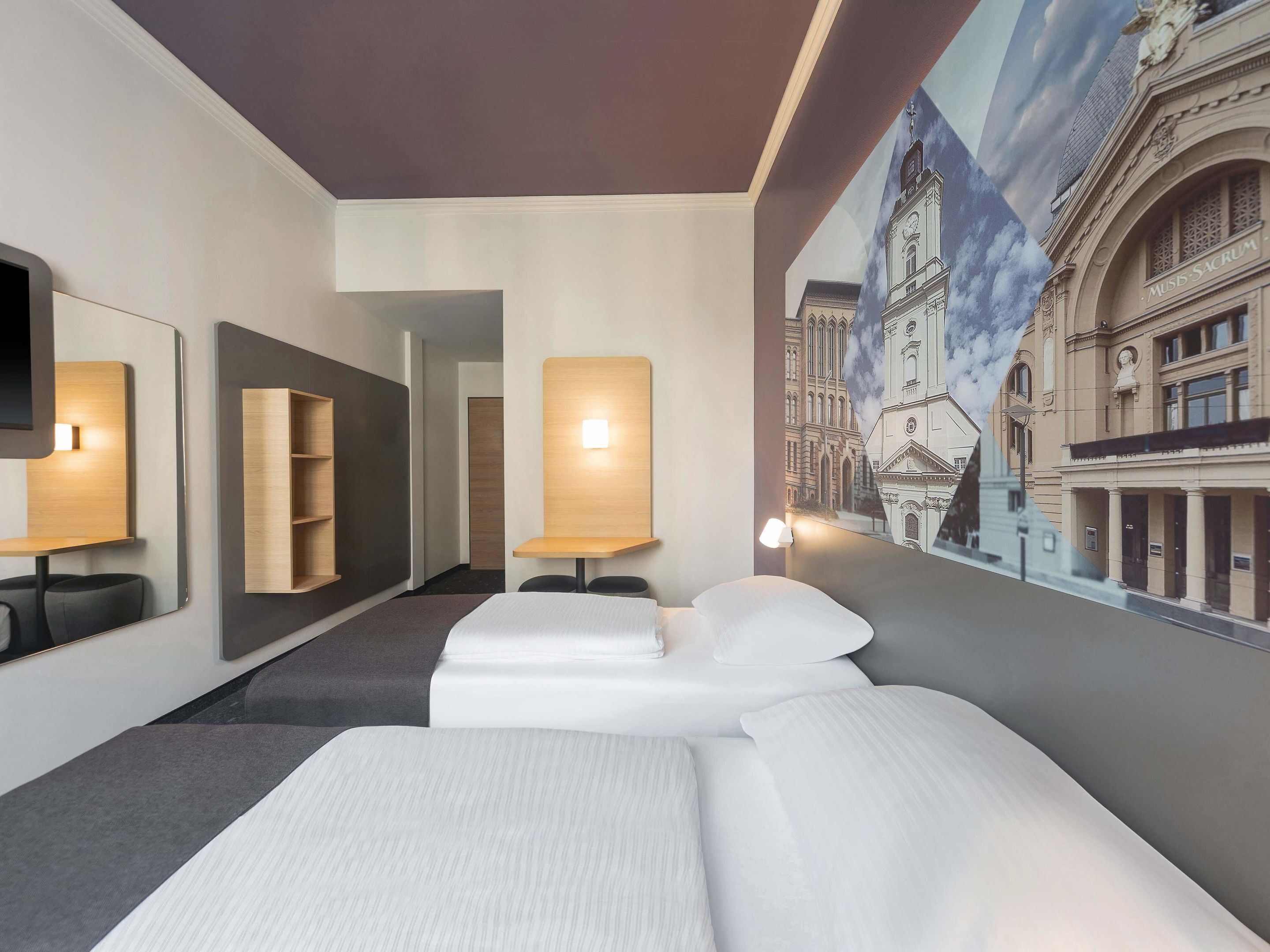 Una camera d'albergo con un letto grande, una scrivania, una sedia, uno specchio e una mensola a parete.