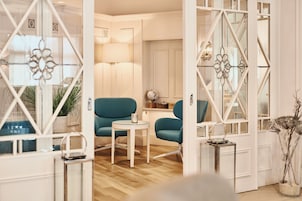 A room with a teal armchair, a small round table, and a globe on a shelf.