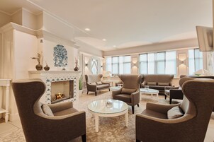 A spacious living room with a fireplace, comfortable seating, and large windows.
