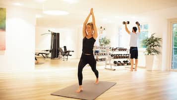 Een sportschool met houten vloeren, trainingsapparatuur en een groot raam.