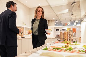 A buffet setup with various food items and a person serving.