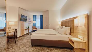 A hotel room with a large bed, a desk, a chair, a TV, and a window with curtains.