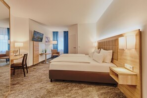 Une chambre d’hôtel avec un grand lit, un bureau, une chaise, une télévision et une fenêtre avec des rideaux.