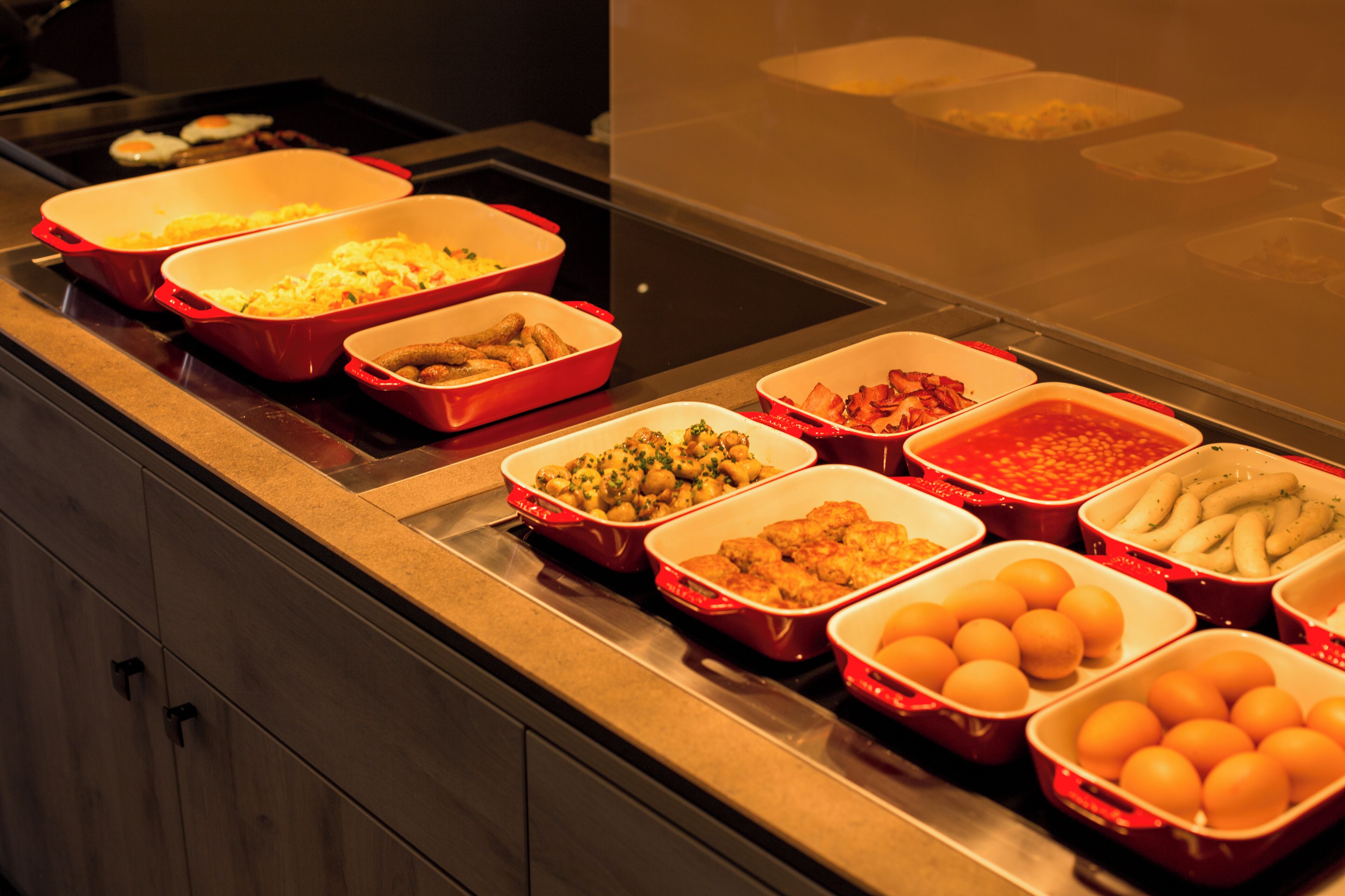 Ein Buffet mit verschiedenen Speisen in roten und weißen Behältern.