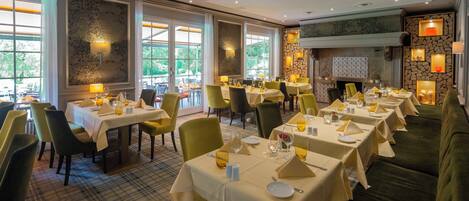 A restaurant with multiple tables, chairs, and a fireplace.