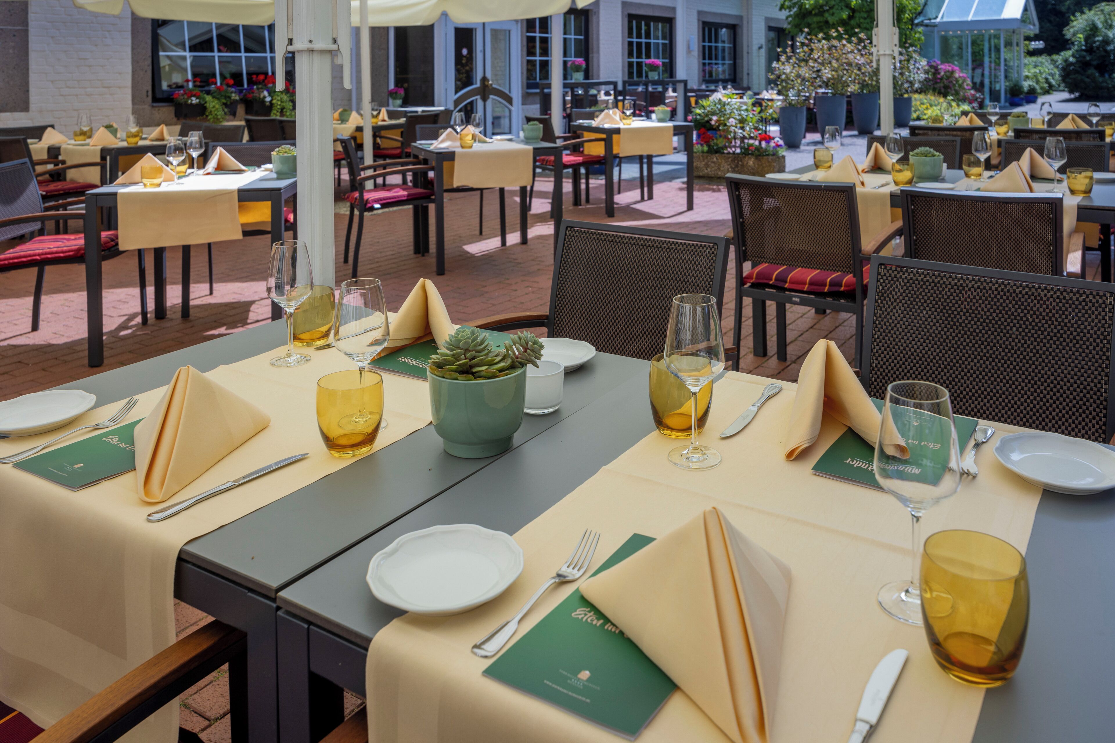 A restaurant with tables set for dining, outdoor seating, and a view of the building in the background.