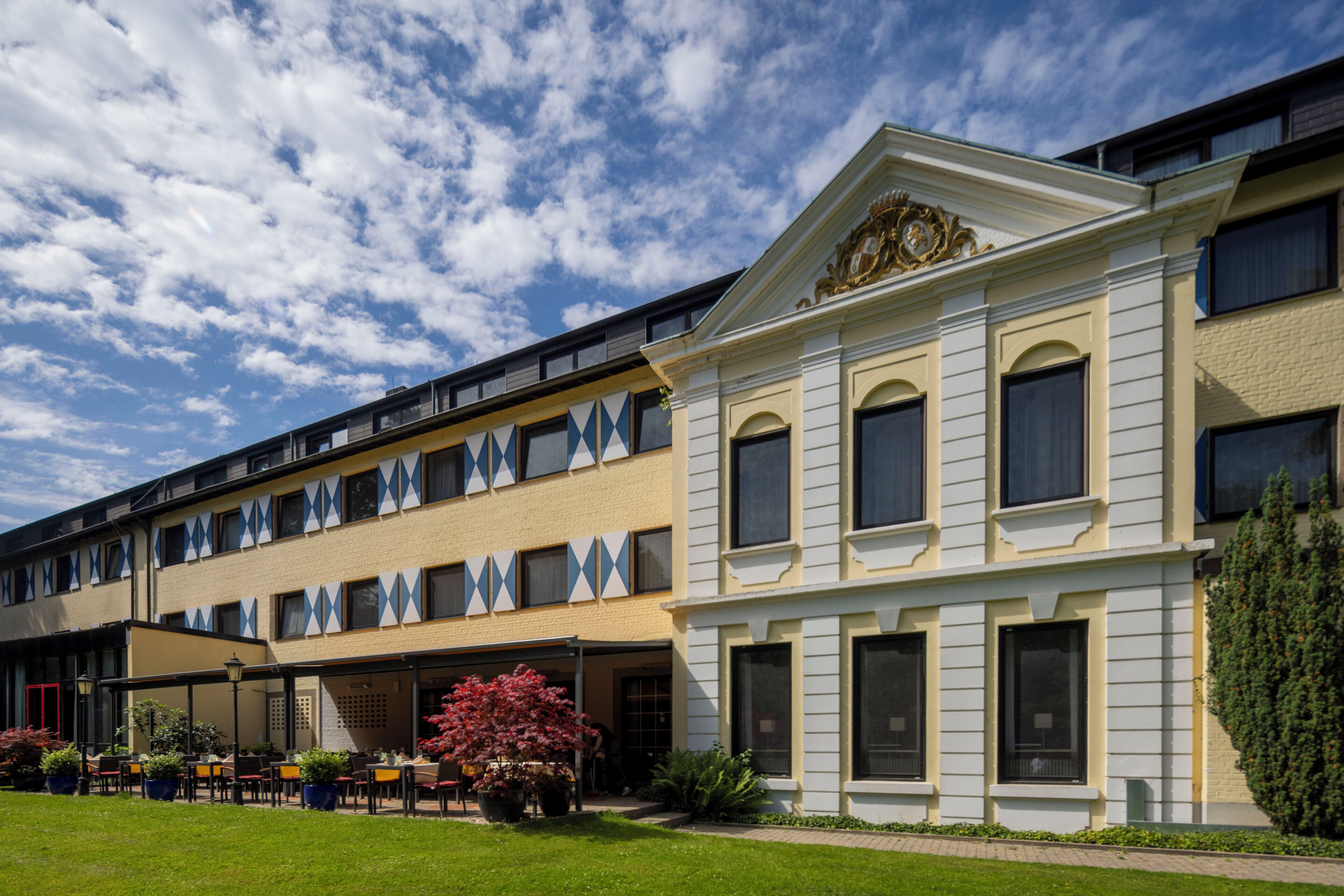 Um hotel com área de estar coberta ao ar livre, um gramado bem cuidado e estilo arquitetônico clássico.