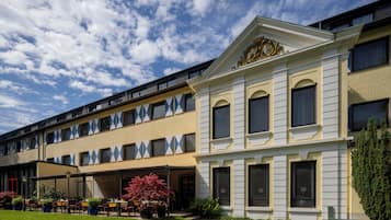 Um hotel com área de estar coberta ao ar livre, um gramado bem cuidado e estilo arquitetônico clássico.