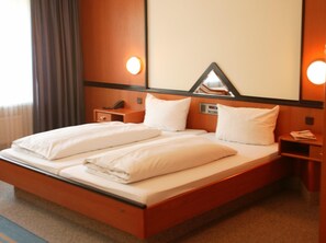 A hotel room with a large bed, bedside tables, a mirror, and wall-mounted lights. - Top Hotel Senator Munich (Munich)