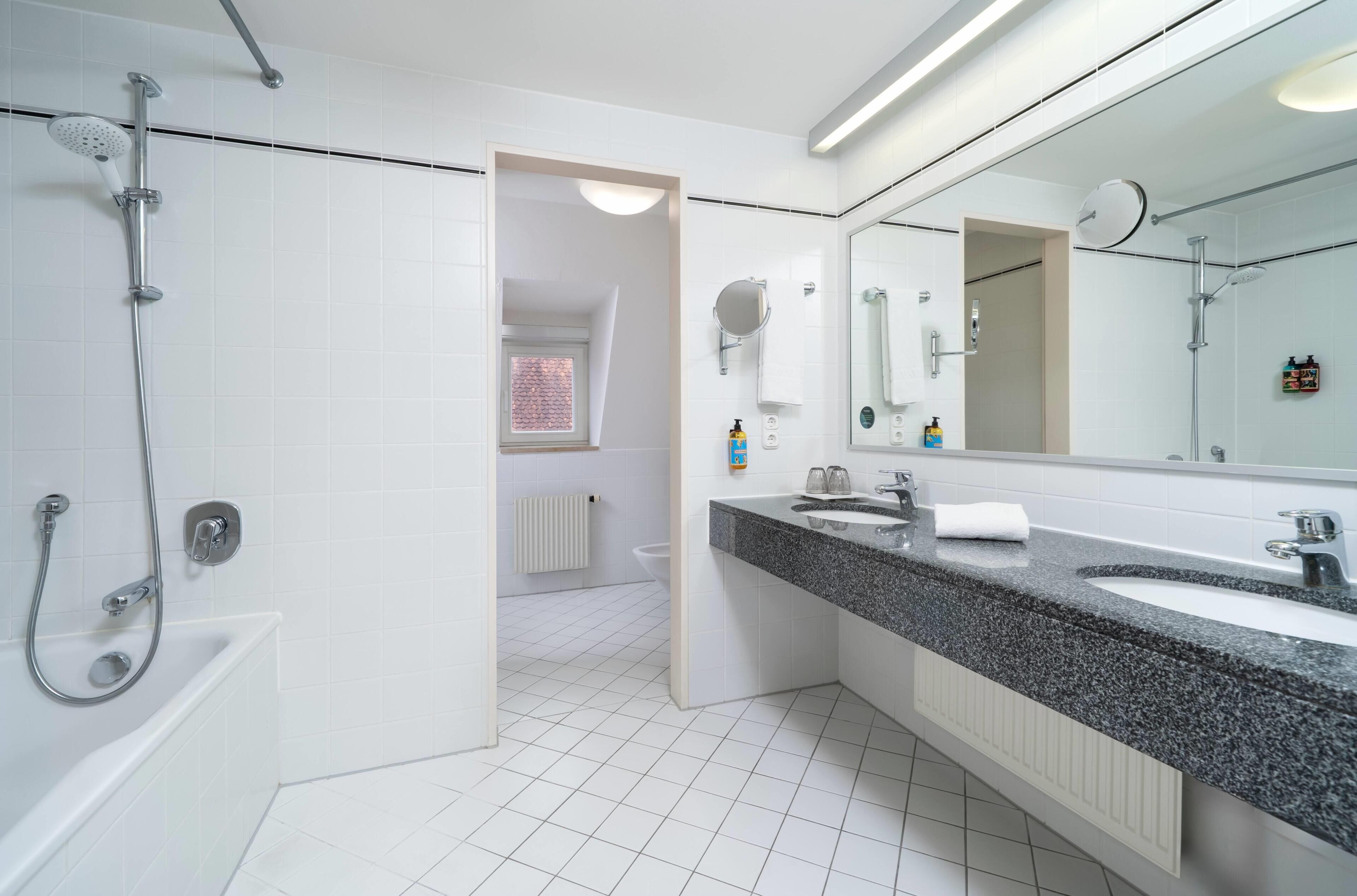 Een moderne badkamer met douche, wastafel en grote spiegel.