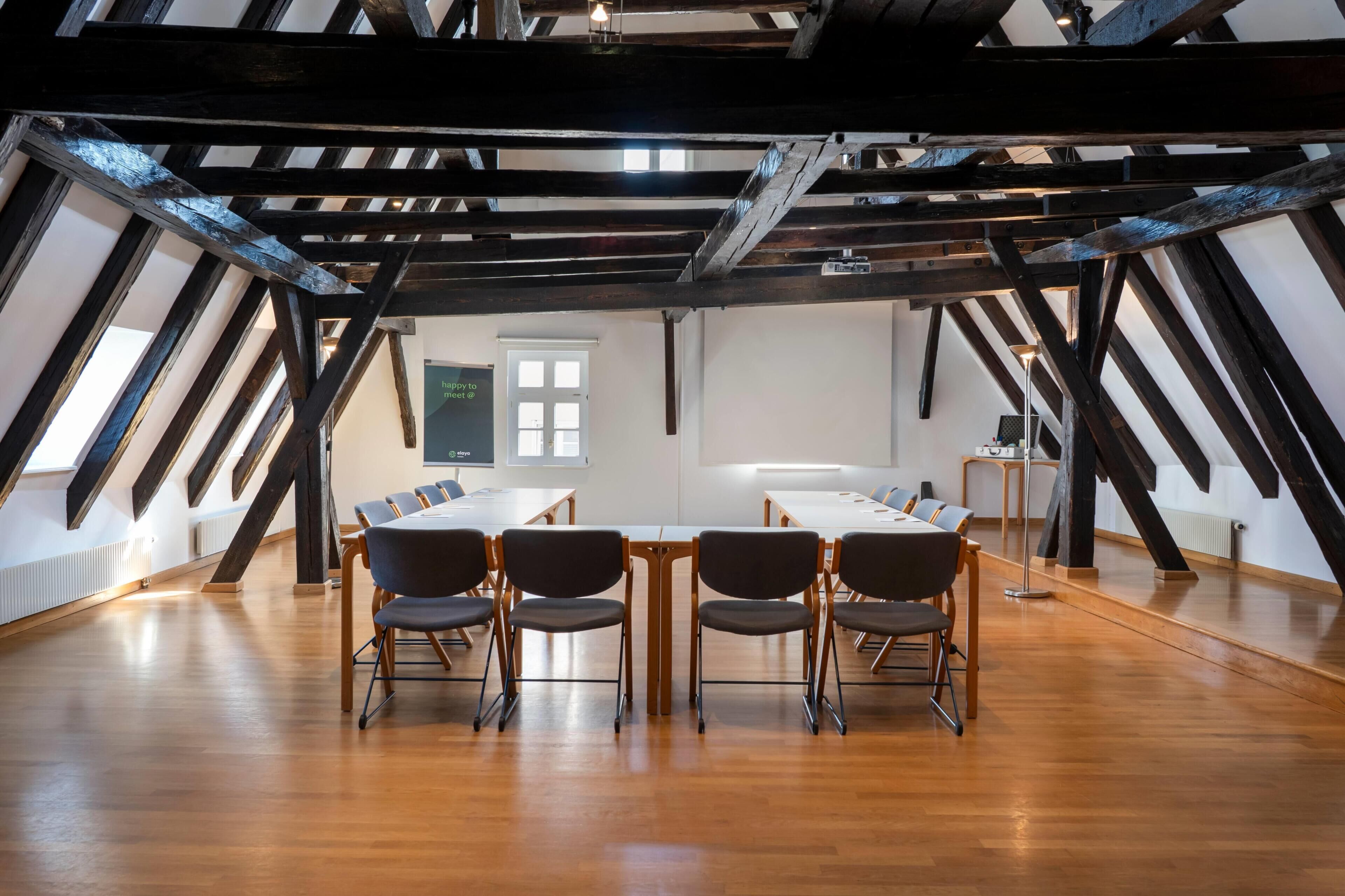 Ein Konferenzraum mit Holzboden, einem langen Tisch und Stühlen.