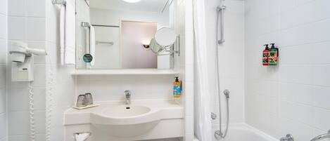 Un baño moderno con lavamanos, espejo y ducha blancos.
