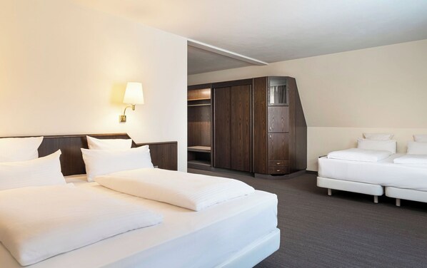 Una habitación de hotel con una cama grande, una cama más pequeña, un armario y un escritorio.
