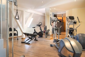 Ein modernes Fitnessstudio mit verschiedenen Trainingsgeräten, darunter Laufbänder, Ergometer und Kurzhanteln.