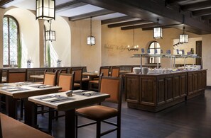 L’intérieur d’un restaurant se caractérise par de hauts plafonds, des poutres apparentes et un îlot central où est installé un buffet.