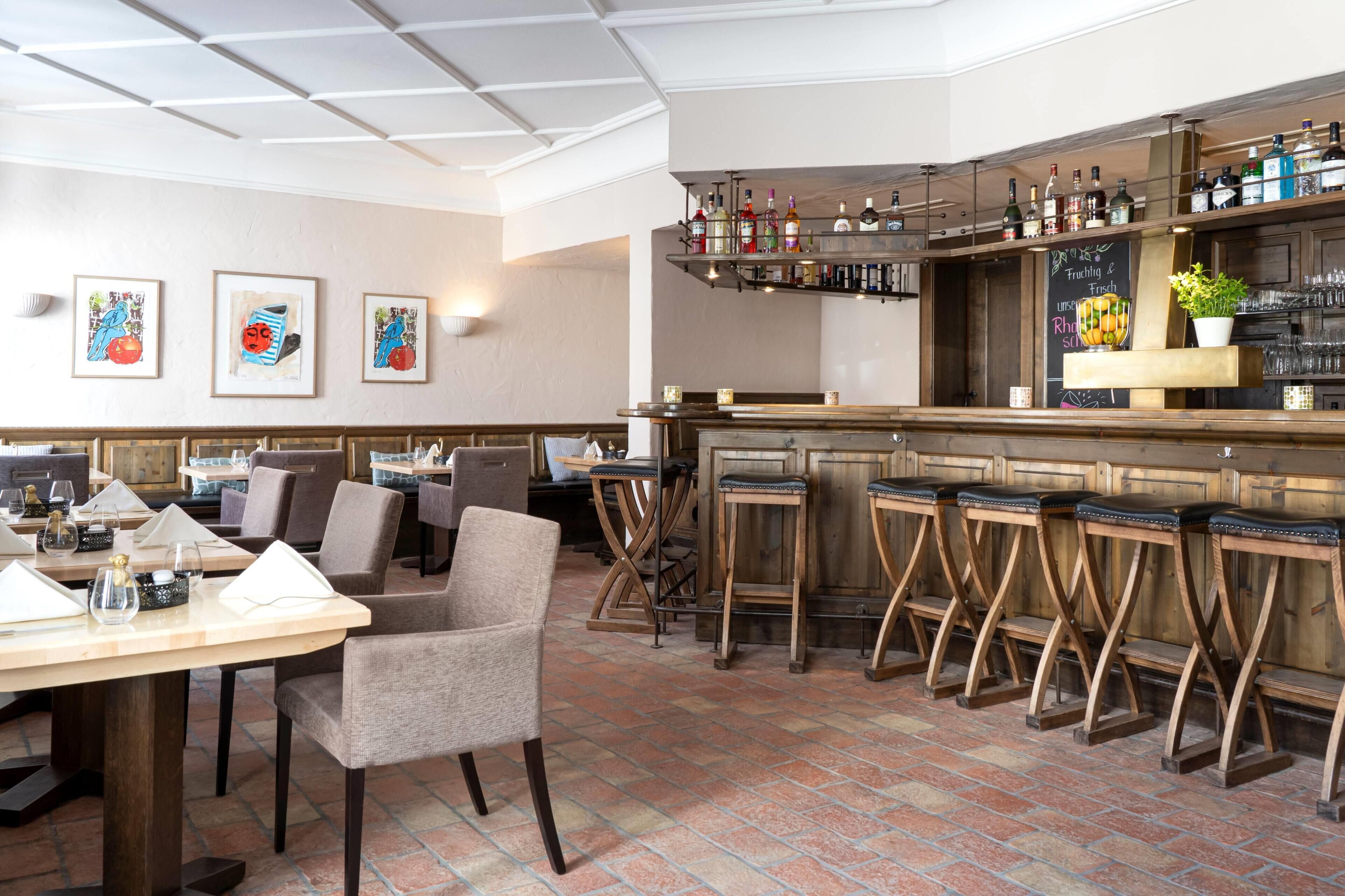 A restaurant interior with a bar area, seating arrangements, and artwork on the walls.