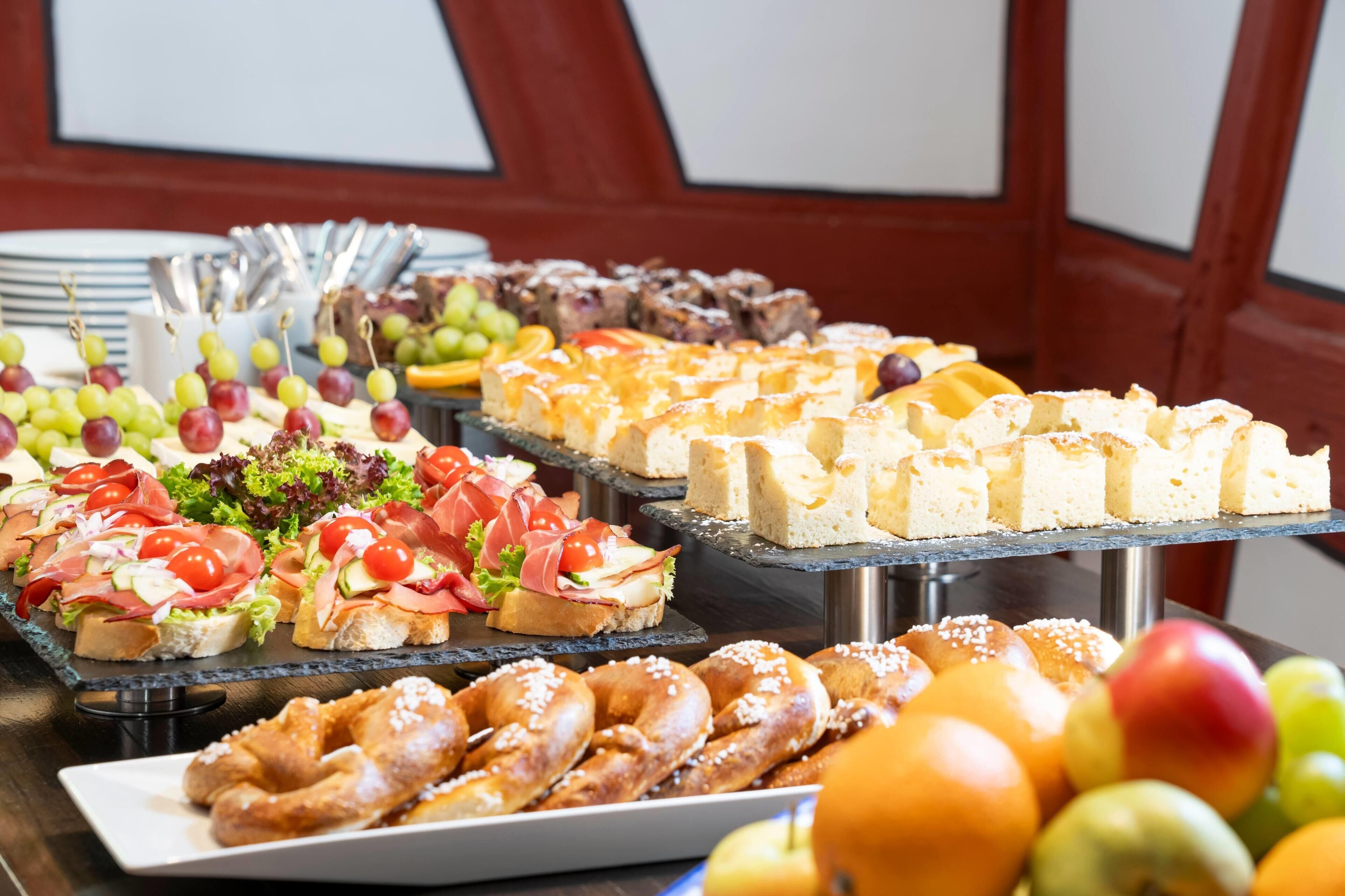 A buffet with various food items including sandwiches, pastries, and fruits.