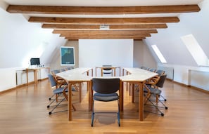 Une salle de conférence dotée d’une grande table ovale, de nombreuses chaises, d’un tableau blanc et d’un projecteur.