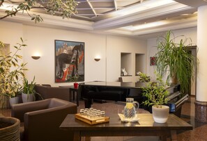 A modern living room with a black piano, a pool table, and a large abstract painting. - elaya hotel noerdlingen, Trademark by Wyndham (Nördlingen)