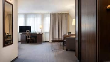 A hotel room with a desk, chair, TV, and a bed.