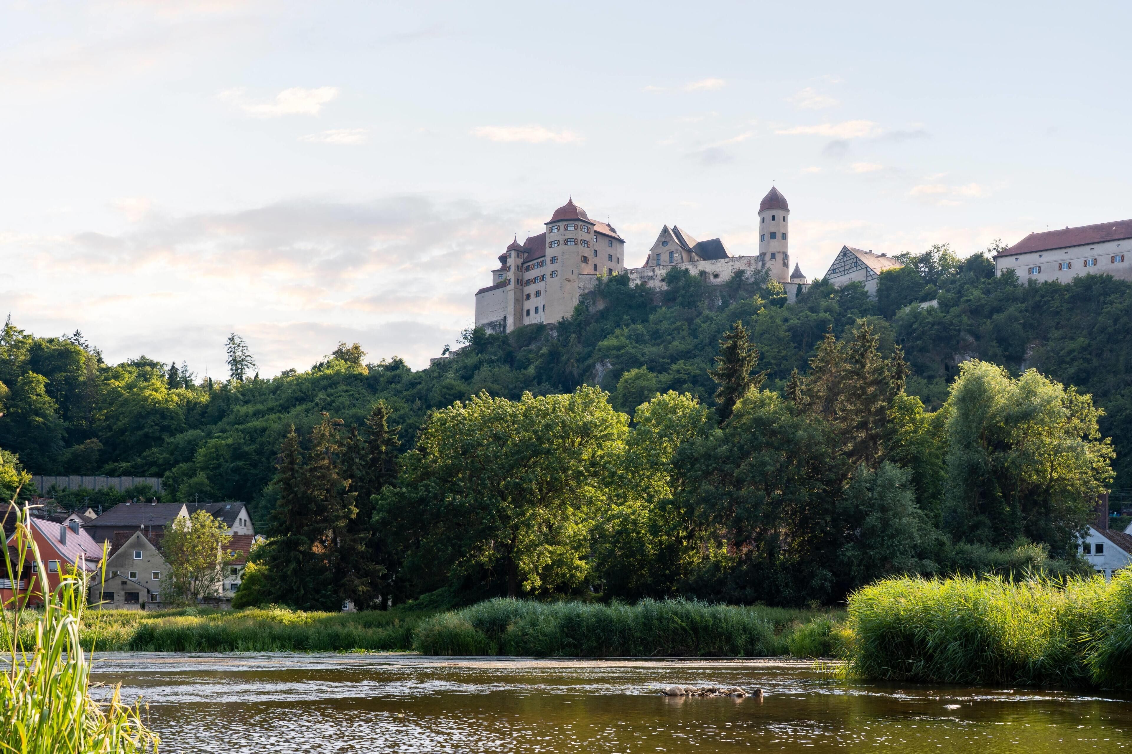 A castle on a hill with a river in the foreground.